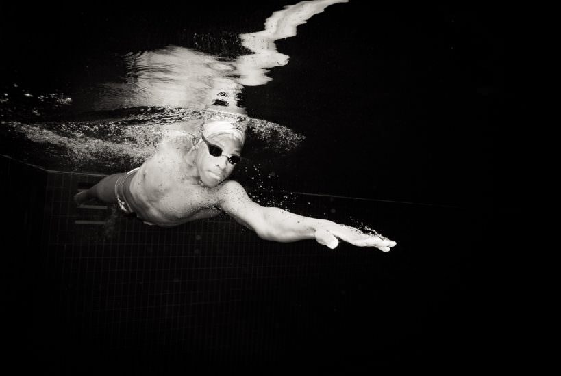 underwater photography of a swimmer with a black background